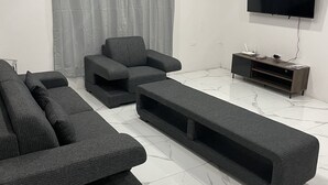 Una sala moderna con un sofá modular, un televisor de pantalla plana y un aire acondicionado instalado en el techo.