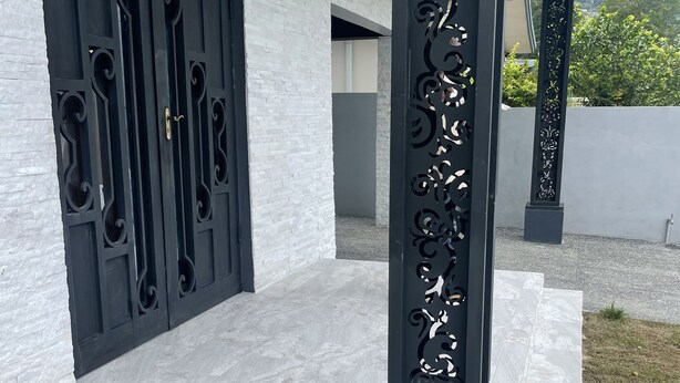Un edificio moderno con fachada de ladrillo blanco, una reja decorativa negra y una columna con motivos de león.