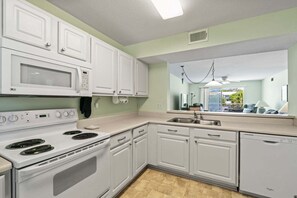 A kitchen with white cabinets, a microwave, stove, and dishwasher.