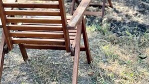 A wooden chair with a slatted backrest and a small table in an outdoor setting. - Guest House | King Bed | Zen Retreat (Irving)
