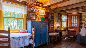 A rustic wooden room with a dining table, chairs, a blue cabinet, and a window with a view of greenery. - Green Plains Cabin (South Charleston)