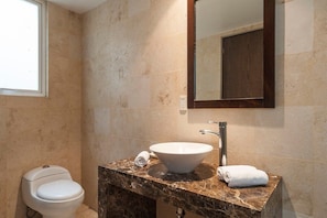 Un bagno con lavabo in marmo, uno specchio e un water.
