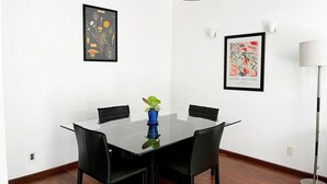 A conference room with a glass table, black chairs, a blue vase with a plant, and two framed artworks on the walls. - Condesa Residence Amsterdam  201- Close from parks (Ciudad de México)