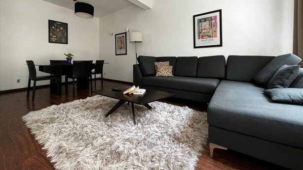 A modern living room with a sectional sofa, a coffee table, a dining table with chairs, and a fluffy rug. - Condesa Residence Amsterdam  201- Close from parks (Ciudad de México)