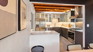 Une cuisine moderne dotée d’appareils électroménagers en acier inoxydable, d’un plafond en bois et d’un îlot central blanc.