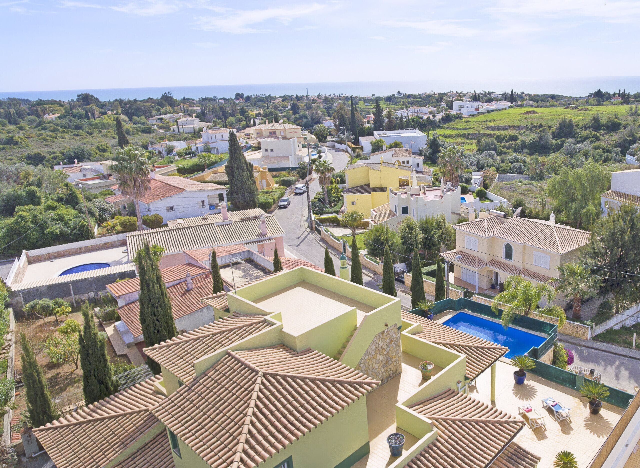 A residential area with houses, a swimming pool, and a view of the sea.