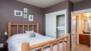 Une chambre à coucher avec un lit en bois, une table de chevet, une lampe et une armoire avec un miroir.