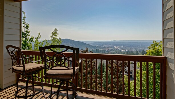 Un balcon avec deux chaises en bois et une vue sur une vallée.