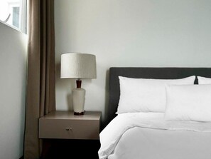 Une chambre d’hôtel avec un lit, une table de chevet avec une lampe et une fenêtre avec des rideaux.