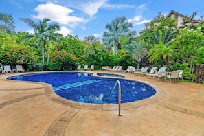 Piscina com espreguiçadeiras e palmeiras.