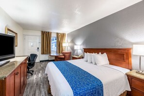 A hotel room with a large bed, a desk with a computer, a chair, a TV, and a window with curtains. - Econo Lodge Phoenix North I-17 (Phoenix)