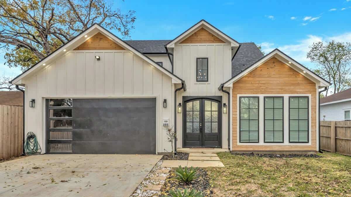 A two-story house with a garage, a front porch, and a small garden area.