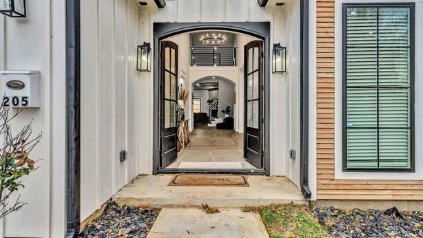 A modern house entrance with a double door, a welcome mat, and a staircase leading to the upper level.