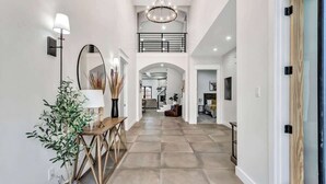 A spacious hallway with a wooden console table, a mirror, and a potted plant.