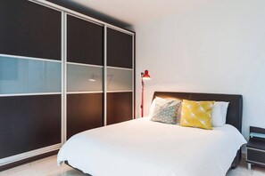 Una camera da letto con un letto, un comodino, una lampada rossa e una porta scorrevole per l'armadio.