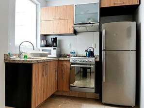 Una cocina con armarios de madera, un refrigerador de acero inoxidable, una estufa y un microondas.
