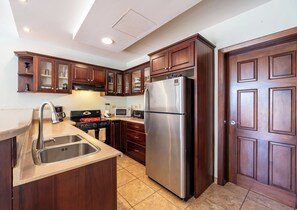A kitchen with wooden cabinets, stainless steel appliances, and a tiled floor.