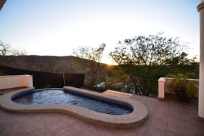 Une piscine à bord incurvé, entourée d’une terrasse carrelée.