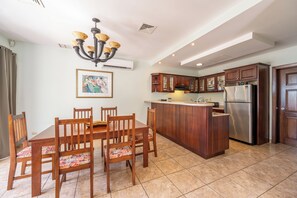 A modern kitchen with a central island, wooden cabinets, and a stainless steel refrigerator.