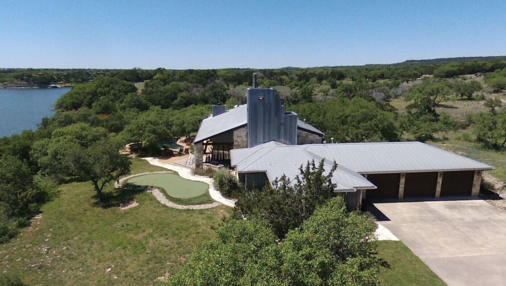 A large house with a swimming pool, a garage, and a view of a lake.