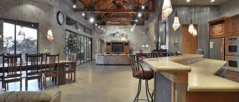 Una cocina amplia con una isla central, vigas de madera e iluminación colgante.