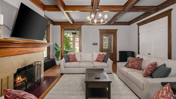 Una sala de estar con chimenea, un televisor montado en la pared y un ventanal grande.