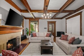 Una sala de estar con chimenea, un televisor montado en la pared y un ventanal grande.