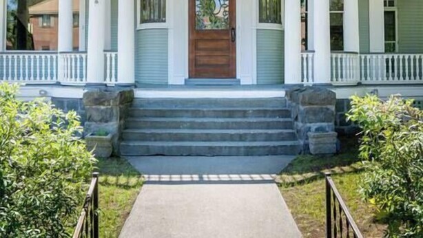 A two-story house with a front porch, a central entrance, and a small garden area. - Entire 2nd and 3rd level of Spacious Historic Home (Spokane)
