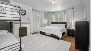A bedroom with a bunk bed, a fireplace, a large bed, a nightstand, and a TV. - Entire 2nd and 3rd level of Spacious Historic Home (Spokane)