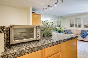 Une cuisine moderne dotée d’un four à grille-pain encastré, d’un plan de travail en granit, de meubles en bois et d’une plante en pot.