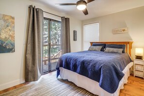 Une chambre à coucher avec un lit, un ventilateur de plafond, une fenêtre avec des stores, un mur orné d’une carte et une table de chevet avec une lampe.