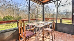 A covered patio with a glass table and wooden chairs, overlooking a grassy area and trees. - Peaceful Mt Sterling Cabin: Deck & Fire Pit! (Mt Sterling)