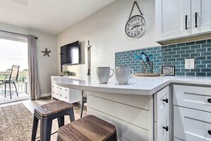Modern kitchen with a clean design, featuring a white countertop, blue-tiled backsplash, and white cabinetry with black handles.