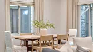 Un coin repas avec une table en bois, des chaises et un vase contenant des plantes vertes.