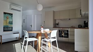 A modern kitchen with white cabinets, a wooden dining table, and two white chairs. - Elaia Silvis on the Mediterranean – 14-meter heated pool (TOUROUZELLE 11200)