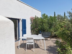 An outdoor patio with a white table and chairs, a blue door, and a bench.