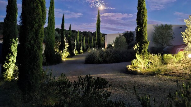 A landscaped garden with tall cypress trees and a building in the background. - Elaia Silvis on the Mediterranean – 14-meter heated pool (TOUROUZELLE 11200)