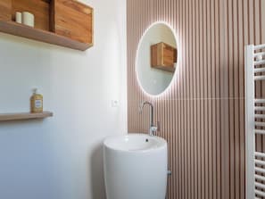 Une salle de bain avec un lavabo blanc, un meuble-lavabo en bois et un miroir.