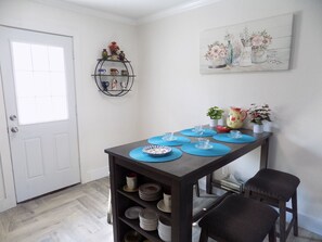 Een eetgedeelte met een tafel voor vier personen, een plank met decoratieve objecten en een schilderij aan de muur.