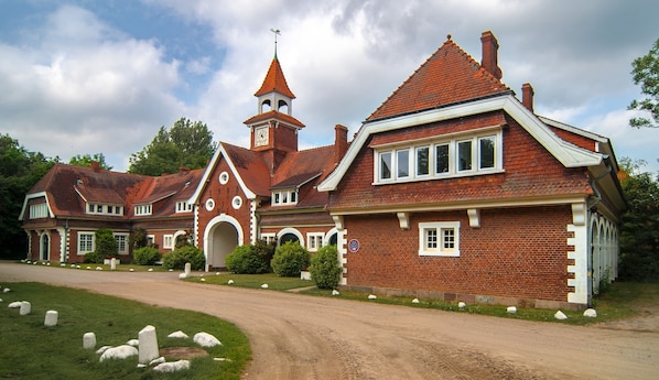 Un grand bâtiment traditionnel en briques, doté d’une tour imposante et de nombreuses cheminées.