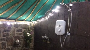 A bathroom with a stone wall, a shower area, and a green-striped tent-like ceiling. - Eco Glamping immersed in nature, ideal for family holidays andromantic getaways! (Whitegate)