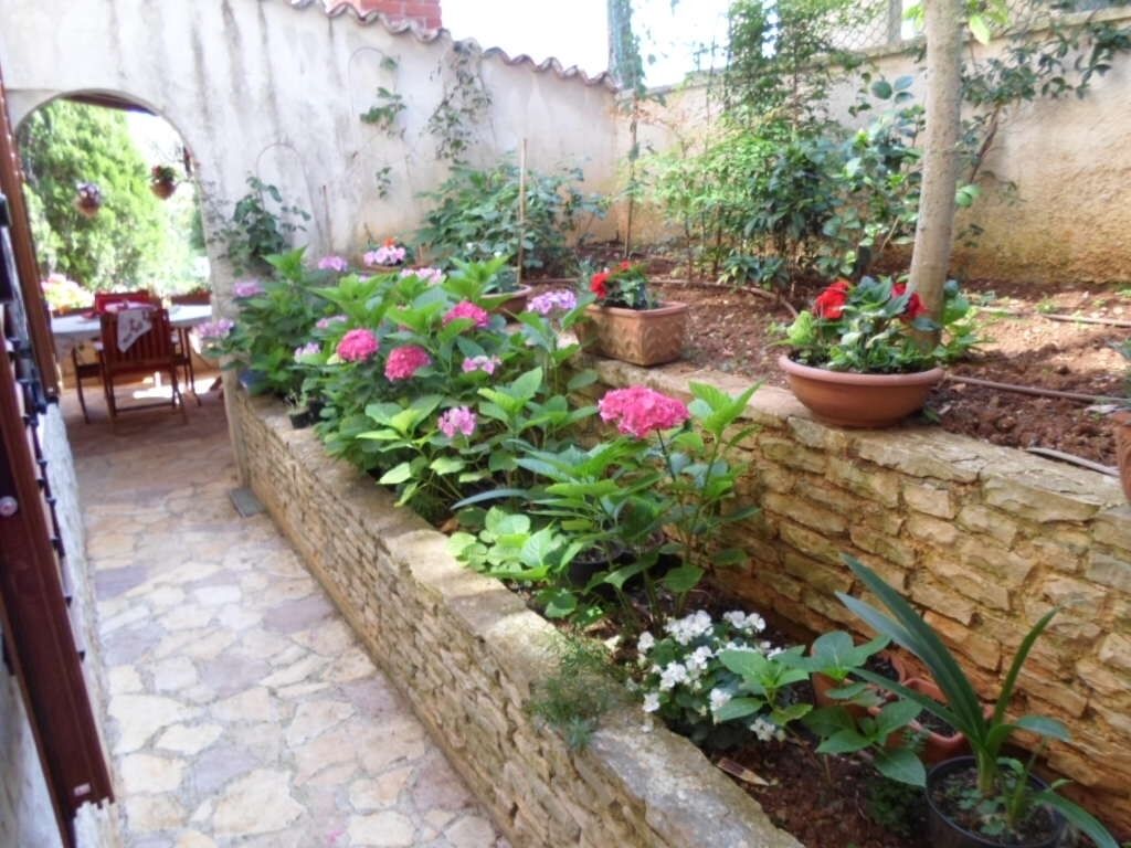 A stone pathway leading to a patio area with potted plants and a rustic wall.