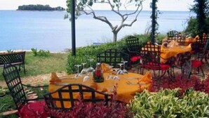 An outdoor dining area with tables set for two, overlooking a body of water. - Apartment in Banjole with Air condition, WIFI, Washing machine (3360-2) (Banjole)
