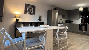 A modern kitchen with a white table and chairs, a Buddha painting, and a built-in oven. - Shrewsbury Townhouse with Open Plan Living (Shrewsbury)