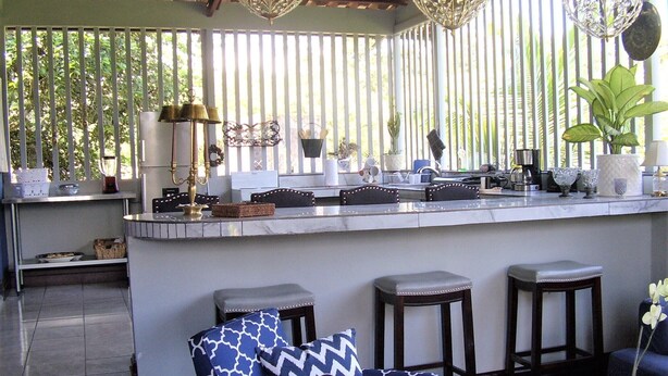 A kitchen with a bar area, featuring a marble countertop, bar stools, and a hanging light fixture.