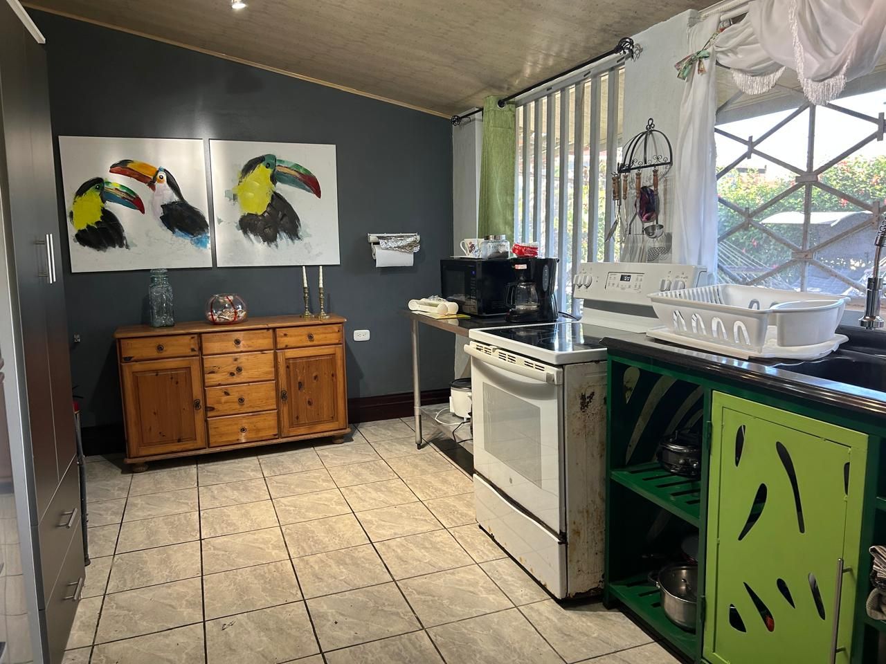 A kitchen with a wooden cabinet, a white stove, and a green cabinet with cut-out designs.