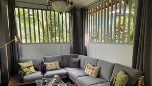 A modern living room with a grey sectional sofa, a glass coffee table, and a wicker side table.