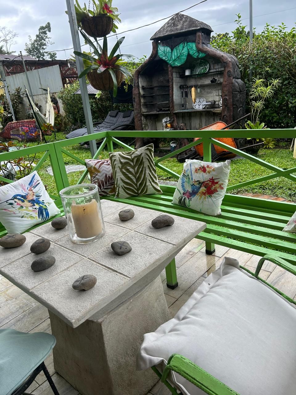 A patio with a table set for two, featuring a candle, rocks, and decorative pillows.