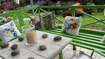 A patio with a table set for two, featuring a candle, rocks, and decorative pillows.