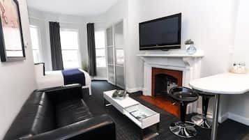Una habitación de hotel moderna con sofá, televisor de pantalla plana, chimenea y zona de comedor.